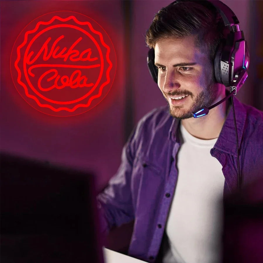 A man wearing headphones is looking at a computer screen with a red neon sign featuring a Coca-Cola bottle cap design.