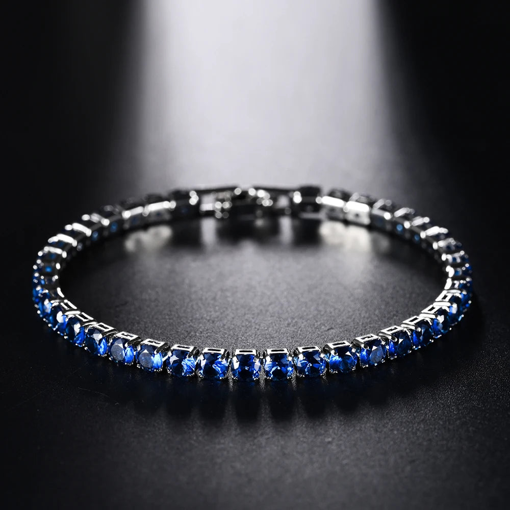 Gros plan d'un bracelet de tennis en diamant bleu avec sertissage micro pavé sur une surface sombre.