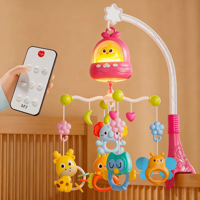 A musical crib mobile featuring a pink rattle and a yellow baby figure, suspended by a white arch, with a remote control near