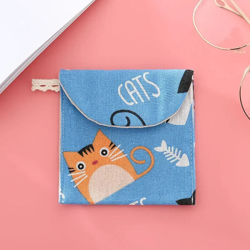 A blue fabric pouch for cosmetics featuring a cat design and a black clasp closure.