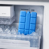 Blue reusable gel ice blocks stacked in a clear ice cube tray inside a refrigerator compartment.