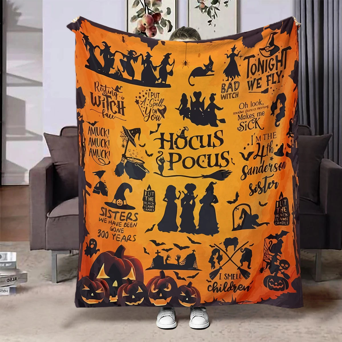 An orange Halloween themed flannel throw blanket featuring silhouettes of witches, bats, pumpkins, and spooky elements.
