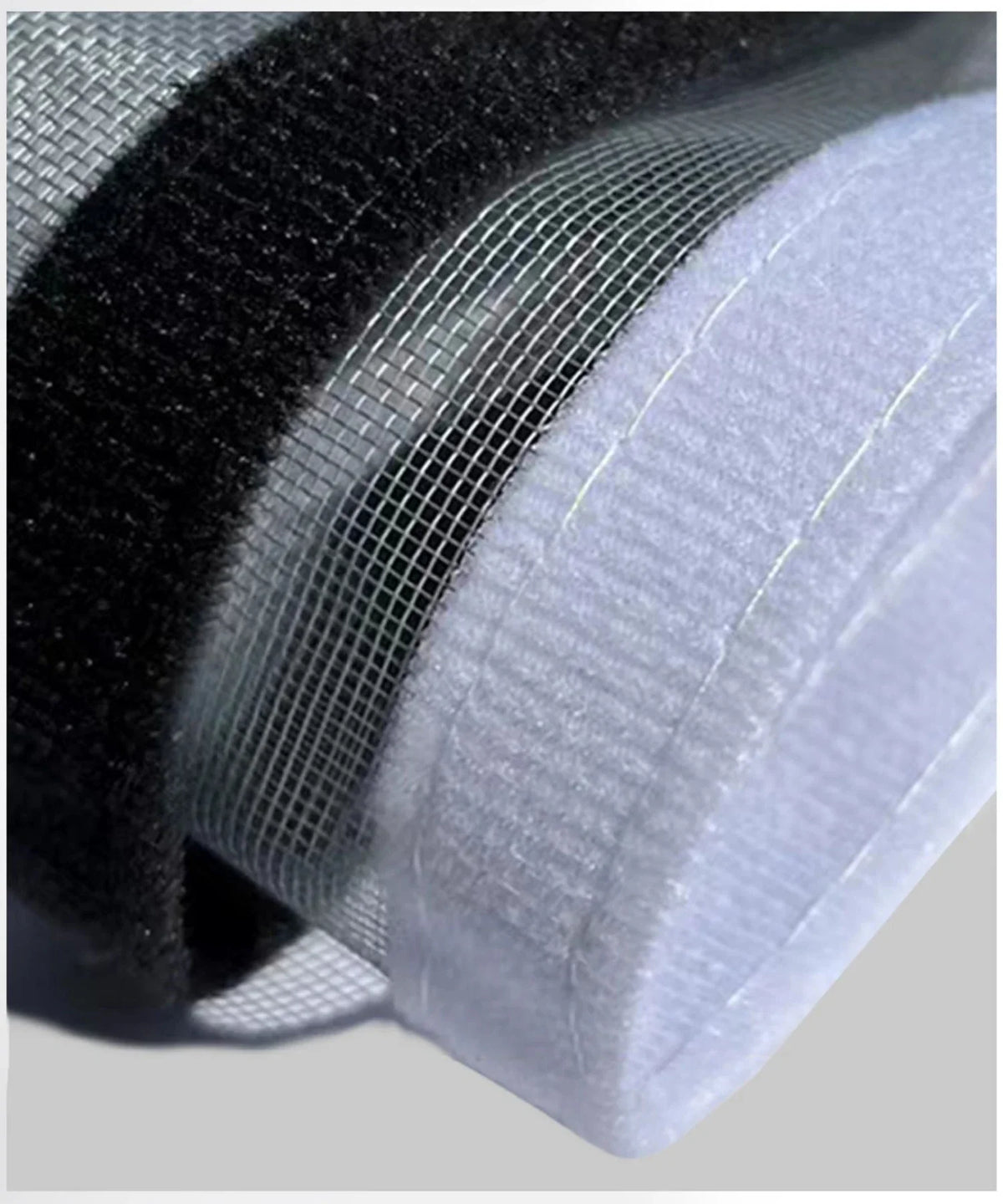 Close-up of a white reusable self-adhesive mosquito window screen material layered over black mesh fabric.
