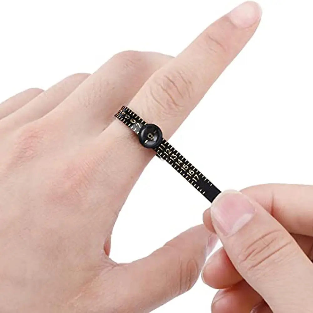 A hand is holding a black ring sizer measuring tool with a magnifier, showing the scale and mechanism.