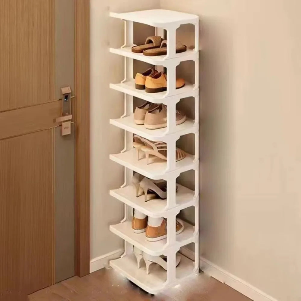 A white stackable vertical shoe rack with multiple tiers holding various pairs of shoes against a light wall.