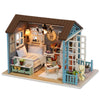 A wooden miniature dollhouse kit featuring a bedroom with furniture and decorative elements.