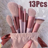 A collection of thirteen makeup brushes in various shades is displayed inside a light pink fabric bag.