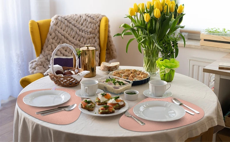 A table setting featuring a meal and tea, surrounded by beige placemats on a white tablecloth.