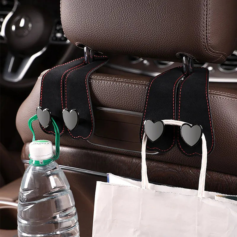 A car seat headrest hook with dual black hooks for hanging bags and phones on a brown leather seat.