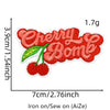 A red cherry embroidered patch featuring a green leaf on white fabric.