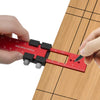 A hand uses an aluminum pocket ruler with a T-track slide stop to measure on a wooden surface.