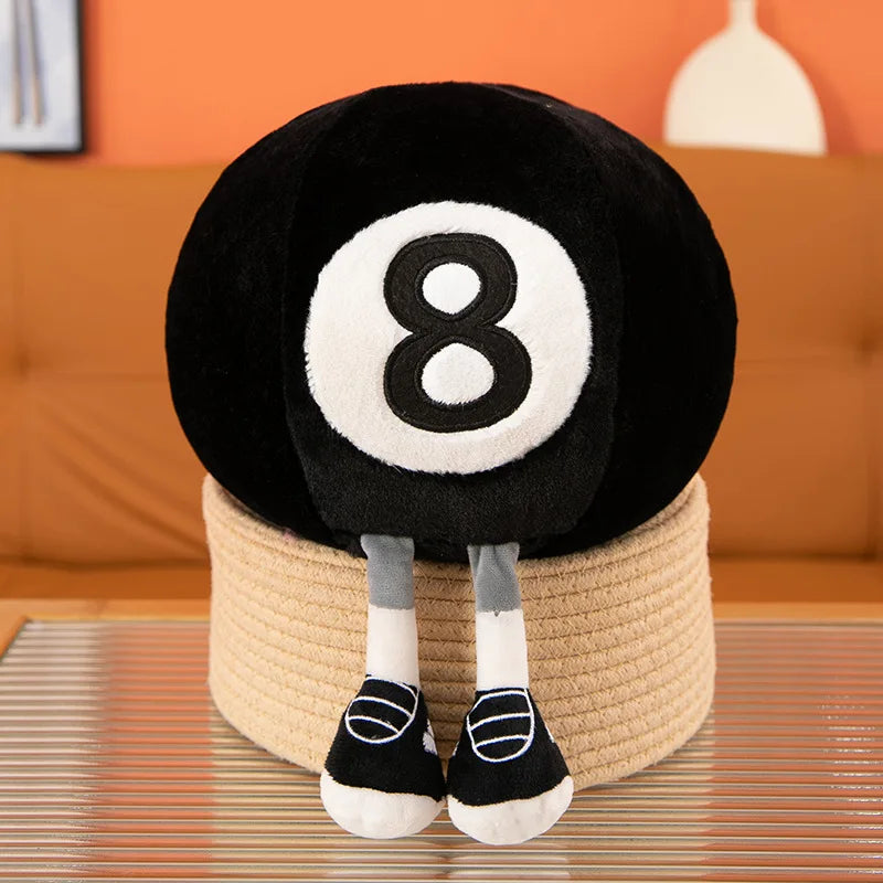 A black and white 8-ball plush toy with white legs resting on a light beige cylindrical base.