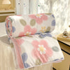 Pink and white floral patterned lightweight comforter with lace trim displayed on a table.