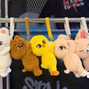 A display of various soft stuffed animal plush dolls including a white cat, an orange bear, a yellow puppy, and a pink rabbit