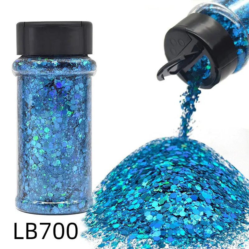 A bottle of LB700 holographic blue glitter nail mix with a black shaker top and loose glitter spilling out.