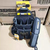 A dark blue electrician tool pouch with a belt clip and kickstand is shown in a cardboard box.
