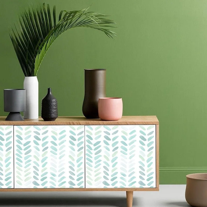 A display featuring a potted palm leaf, various ceramic vases and containers in earthy tones, and a cabinet with green and wh
