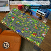 A large gaming mouse pad featuring a vintage city road design with houses and buildings on a wooden desk.