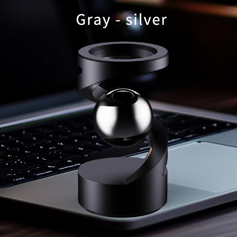 A gray-silver magnetic levitating spinning top resting on a laptop keyboard.