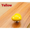 A bright yellow heart-shaped toilet flush button resting on a wooden surface.