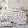 A duvet cover set featuring a heart print in soft gray and white on a bed with matching pillows.