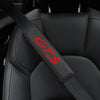A close-up view of a black leather seat belt cover with red stitching and the GTS logo on a car seat.