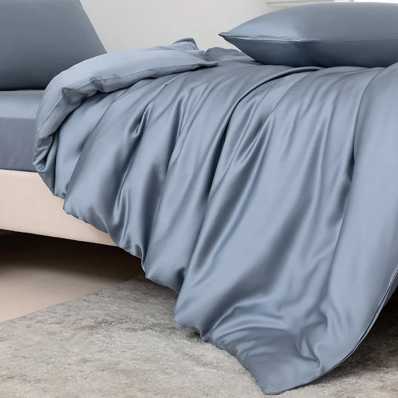 Luxuriöse blaugraue Bambus-Duvetcover-Set, drapiert über einem Bett, zeigt weiche Falten und Stofftextur.