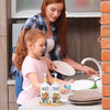 A young girl is helping an adult wash dishes using a Farmhouse Highland Cow Soap Dispenser with Tray.