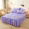Un jupon de lit à imprimé violet avec motifs floraux et volants sur un lit.