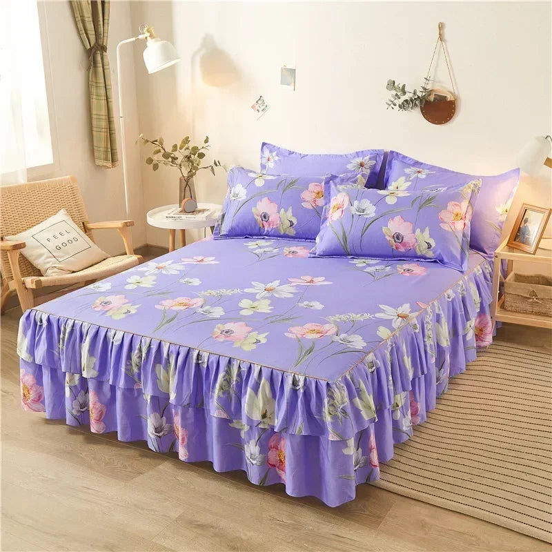 Un jupon de lit à imprimé violet avec motifs floraux et volants sur un lit.