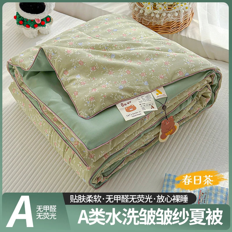 A lightweight summer quilt with a playful cartoon print featuring floral patterns and light green fabric.