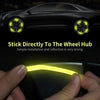 A hand is applying a yellow reflective sticker directly to a car wheel hub for installation.