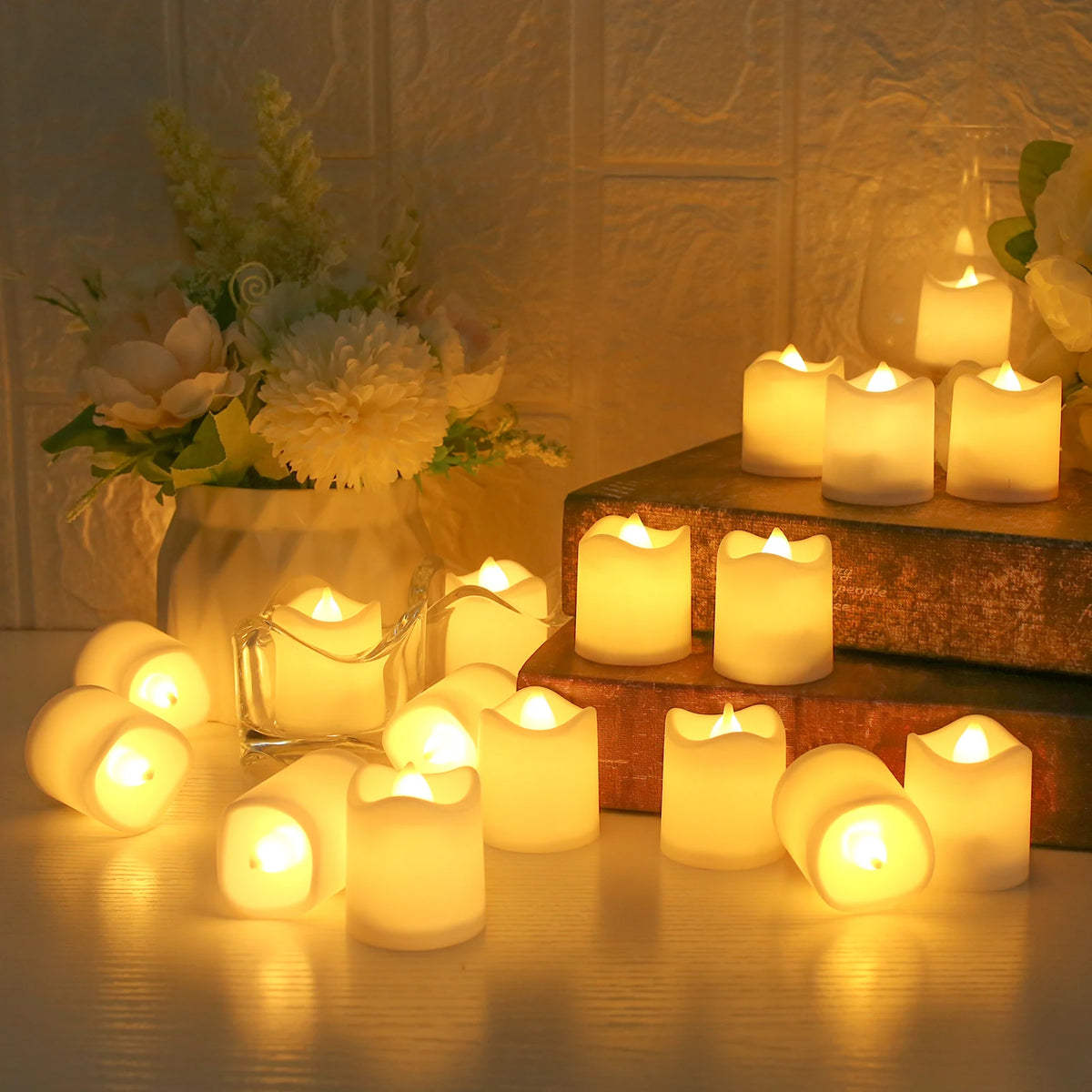 A collection of glowing white LED tea lights arranged on a wooden surface with a floral arrangement in the background.