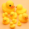 A collection of bright yellow rubber ducklings used as a squeaky bath toy for babies.