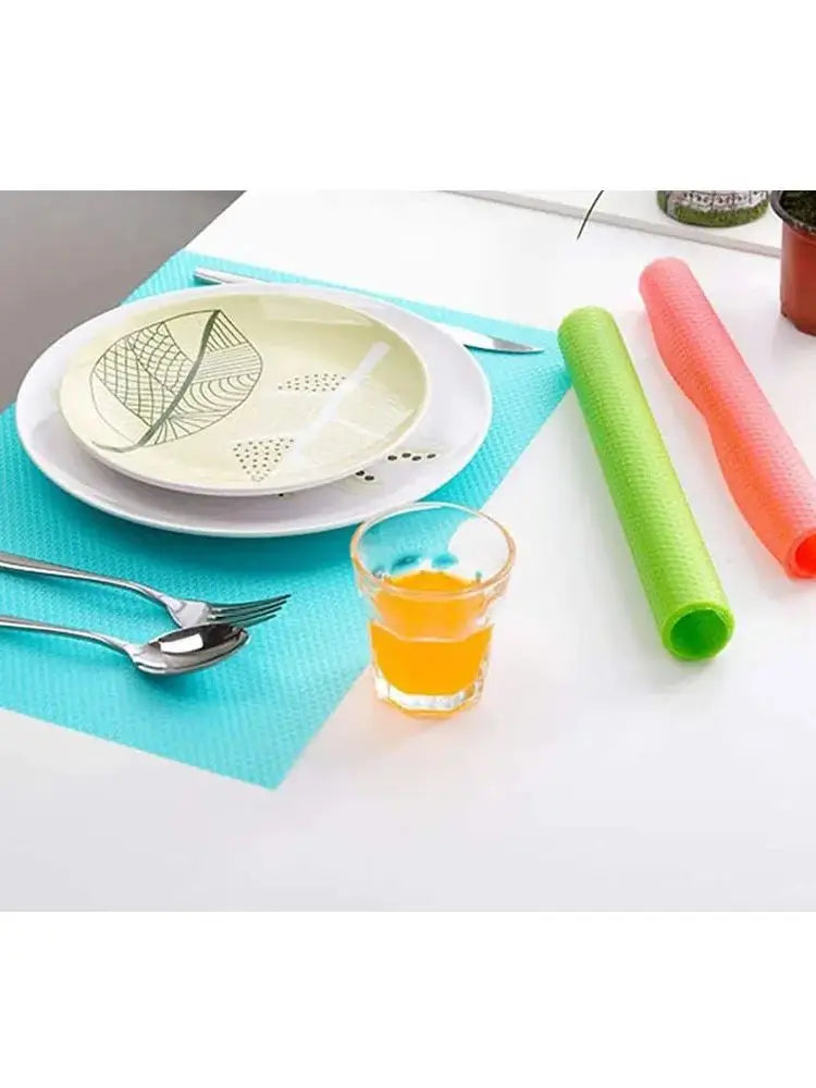A set of colorful silicone mats and a glass are displayed on a white table.