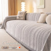 A beige and white knitted sofa cover featuring a fishbone pattern for anti-slip protection.