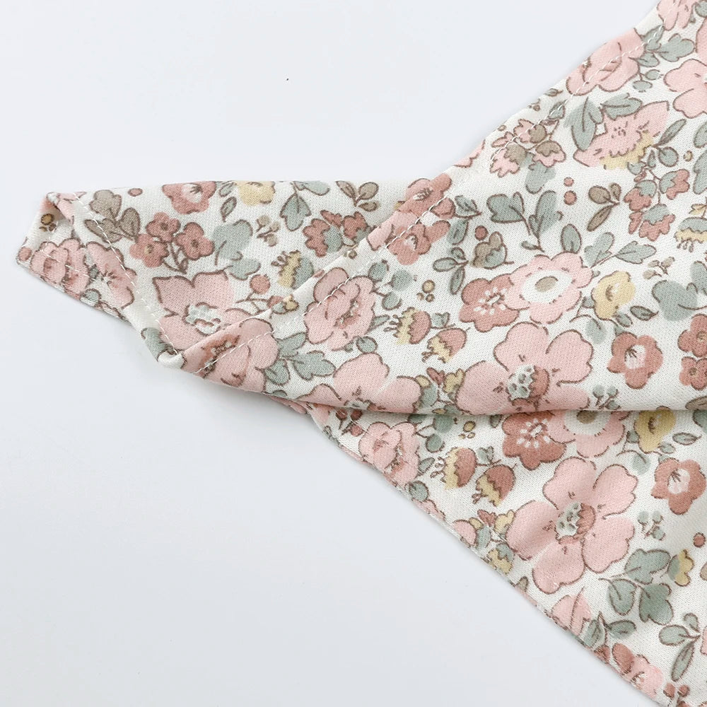 Close-up of a baby comforter fabric featuring a floral pattern in pink, green, and beige tones.