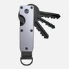 A minimalist aluminum key organizer holding several black keys.