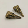 A pair of antique brass or bronze gothic skull and crow head charms for jewelry making.