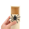 A hand is placing a black spider into a wooden box for a surprise prank.