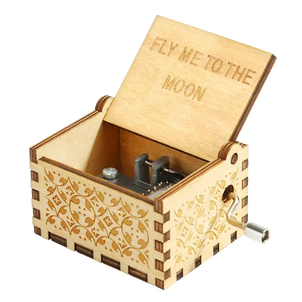 A hand-cranked wooden music box with a lid engraved 'Fly me to the moon' and decorative floral patterns.
