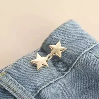 A close-up of a silver star brooch pinned onto blue denim fabric.