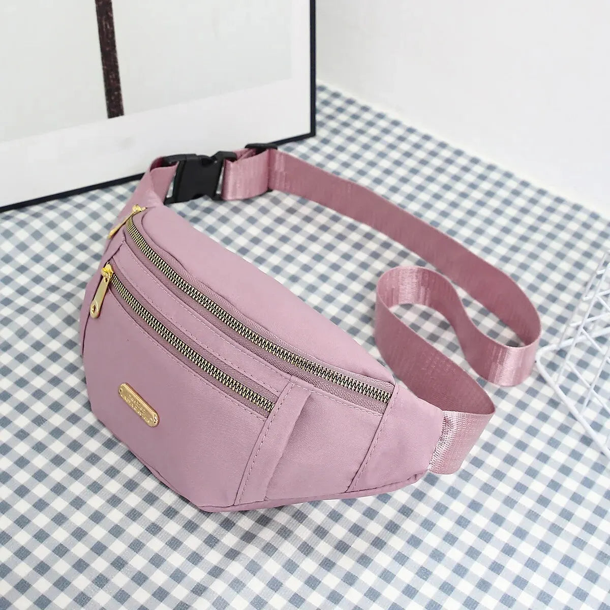 Rosa Damen-Sport-Fanny-Pack mit Reißverschluss und Trageriem lying auf kariertem Untergrund.