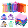 Assorted organza drawstring gift bags in various colors and textures stacked and laid out.