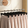 A row of light pink fabric hangers with black clips hanging on a metal rod.