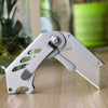 A silver stainless steel folding utility knife with a blade visible, resting on a wooden surface.