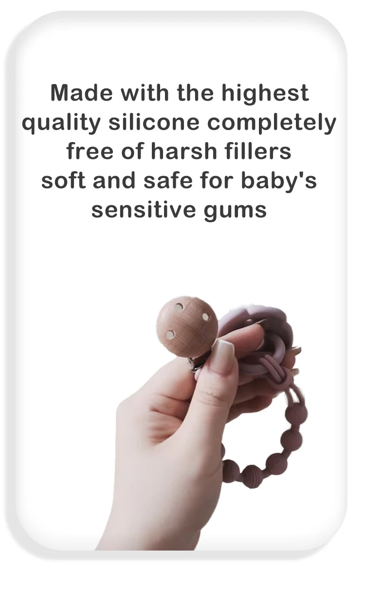 A hand is holding a silicone pacifier clip with a teether, showing the product for baby's sensitive gums.