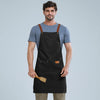 A man wearing a black waterproof adjustable kitchen apron over a gray t-shirt.