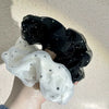A close-up of black and white polka dot mesh scrunchie hair ties being held by a hand.