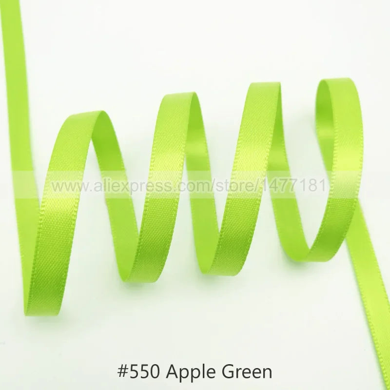 A bright apple green satin ribbon is shown coiled and unwound, demonstrating its texture and drape.